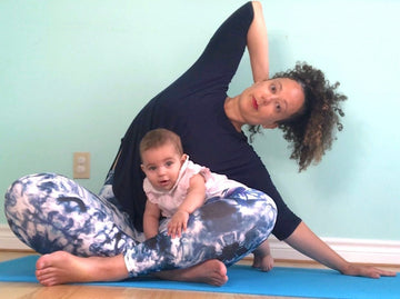 Mother playing with baby on yoga mat.