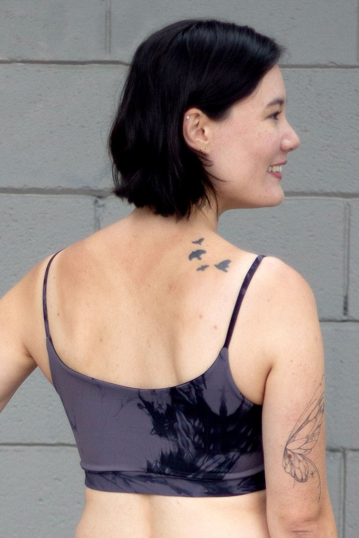 Woman with tattoos wearing a grey swim top