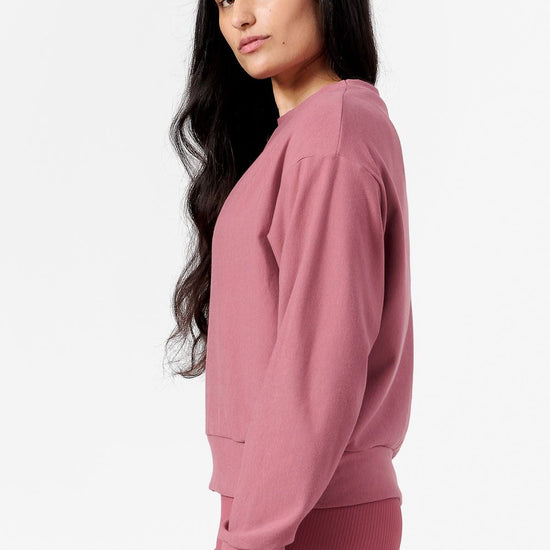 Side of a woman wearing pink crew neck sweatshirt