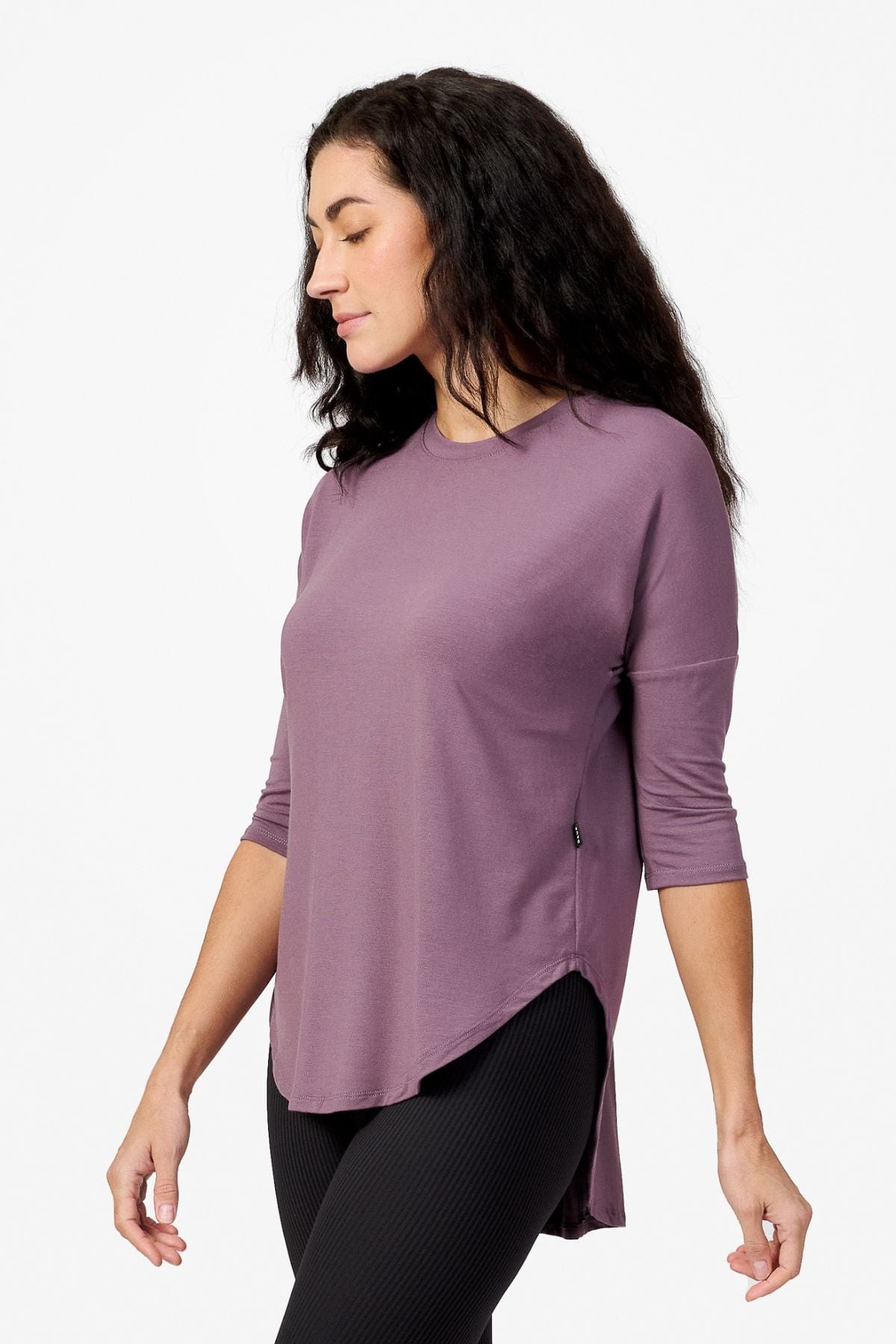 Side of a woman wearing a light purple 3/4 length sleeve shirt