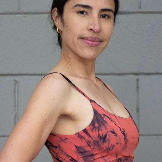 Side of a woman wearing a tie-dye swim top in orange