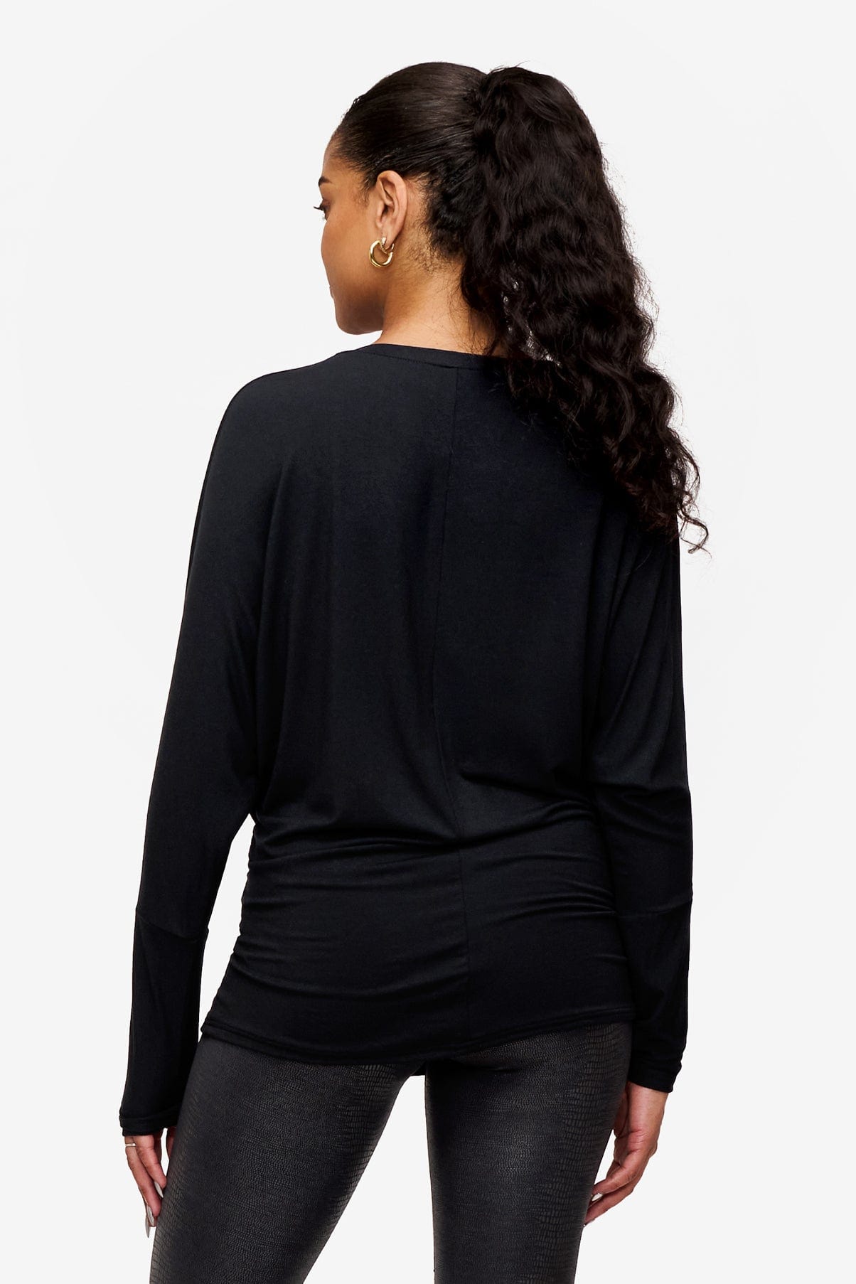 back of a woman wearing a black loose dolman sleeve long sleeve shirt