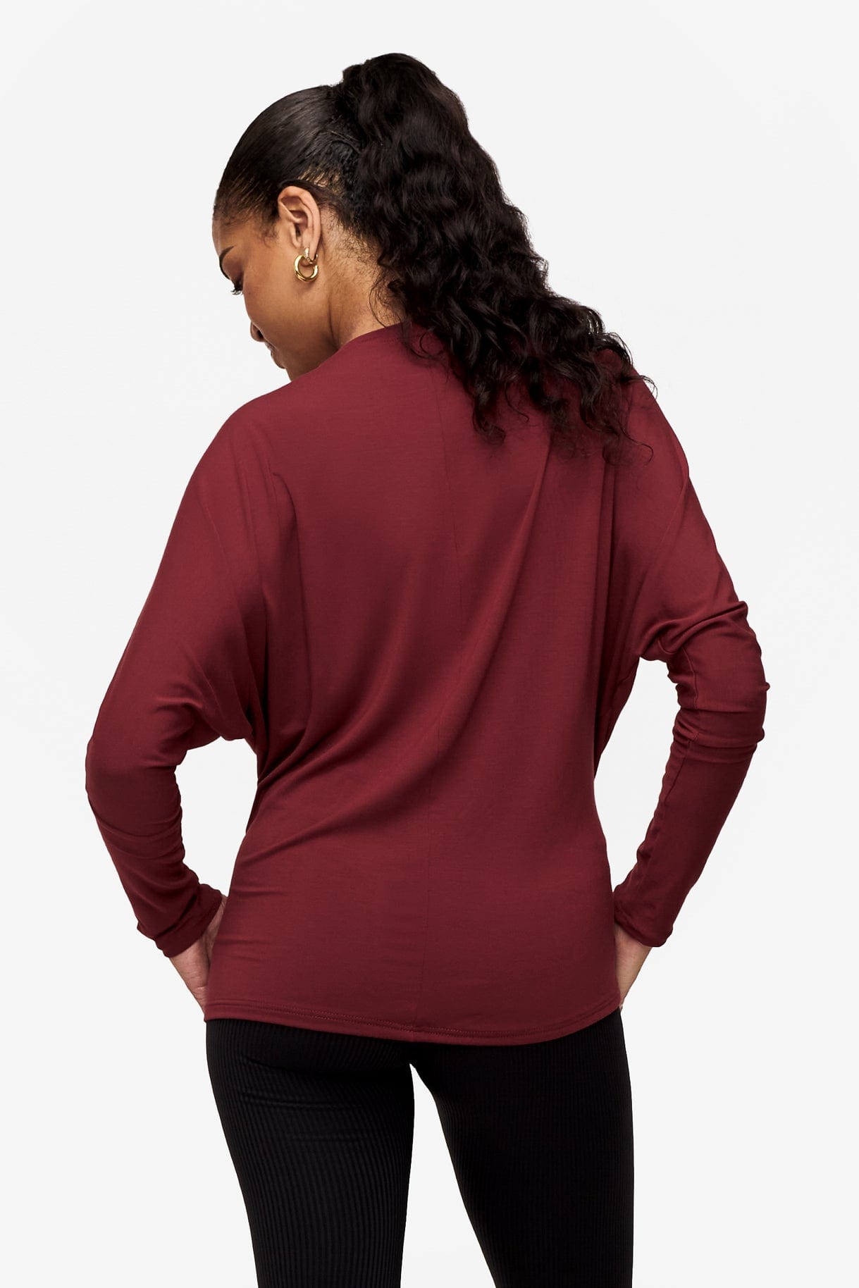 back of a woman wearing a dark red loose sleeve long sleeve shirt
