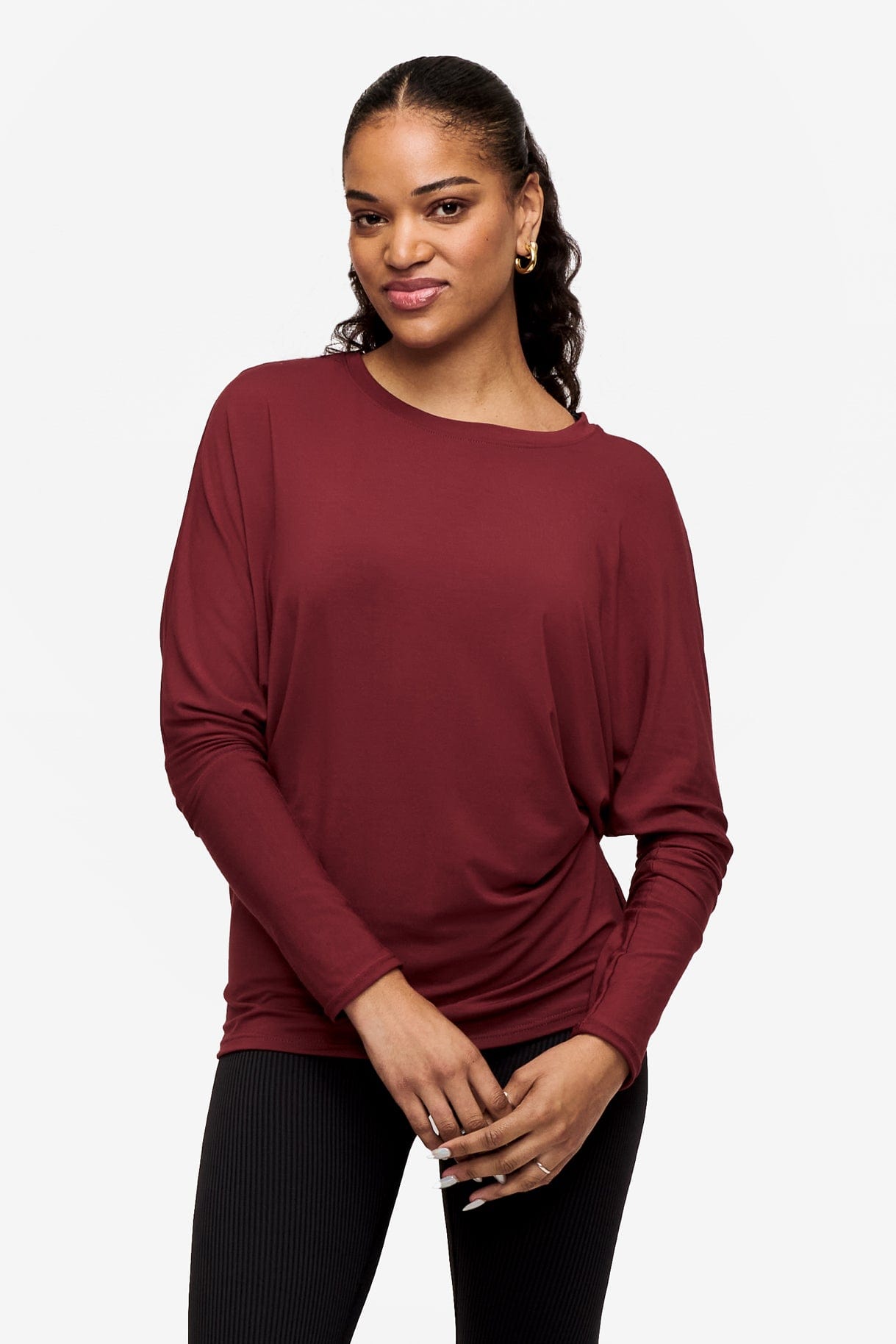 woman wearing a dark red loose sleeve long sleeve shirt with their hands crossed