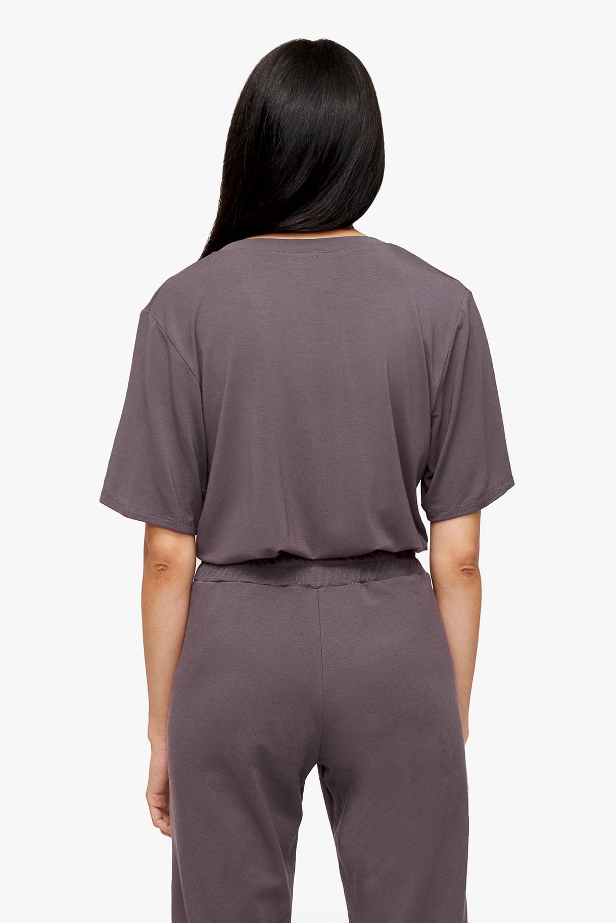 back of a woman wearing deep purple v-neck short sleeve t-shirt tucked in matching pants