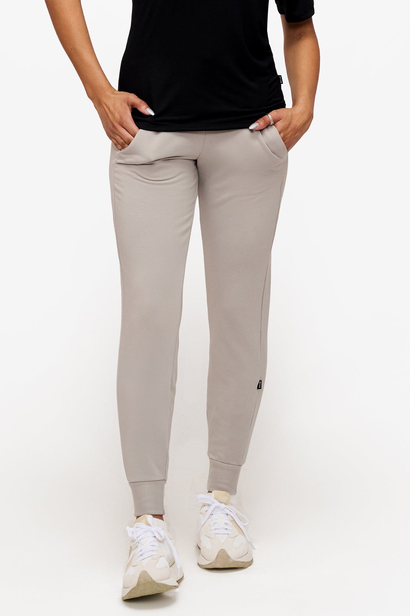 woman wearing light grey sweatpants with hands in the pockets