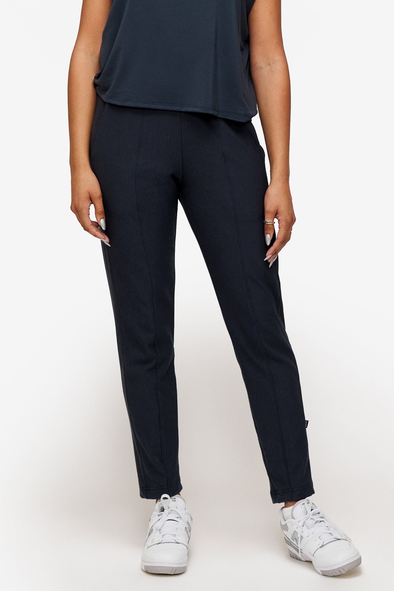 woman wearing dark blue dressy pants with white sneakers