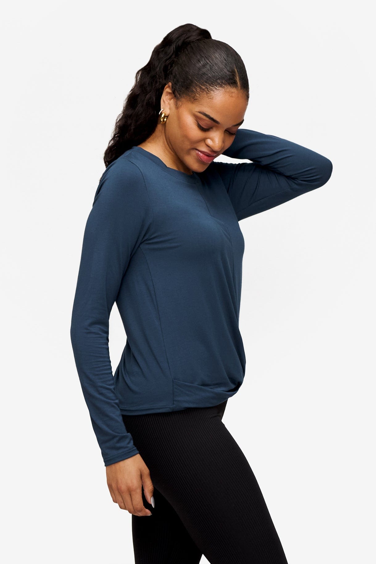 side of a woman wearing a long sleeve shirt with a twist at the front in blue
