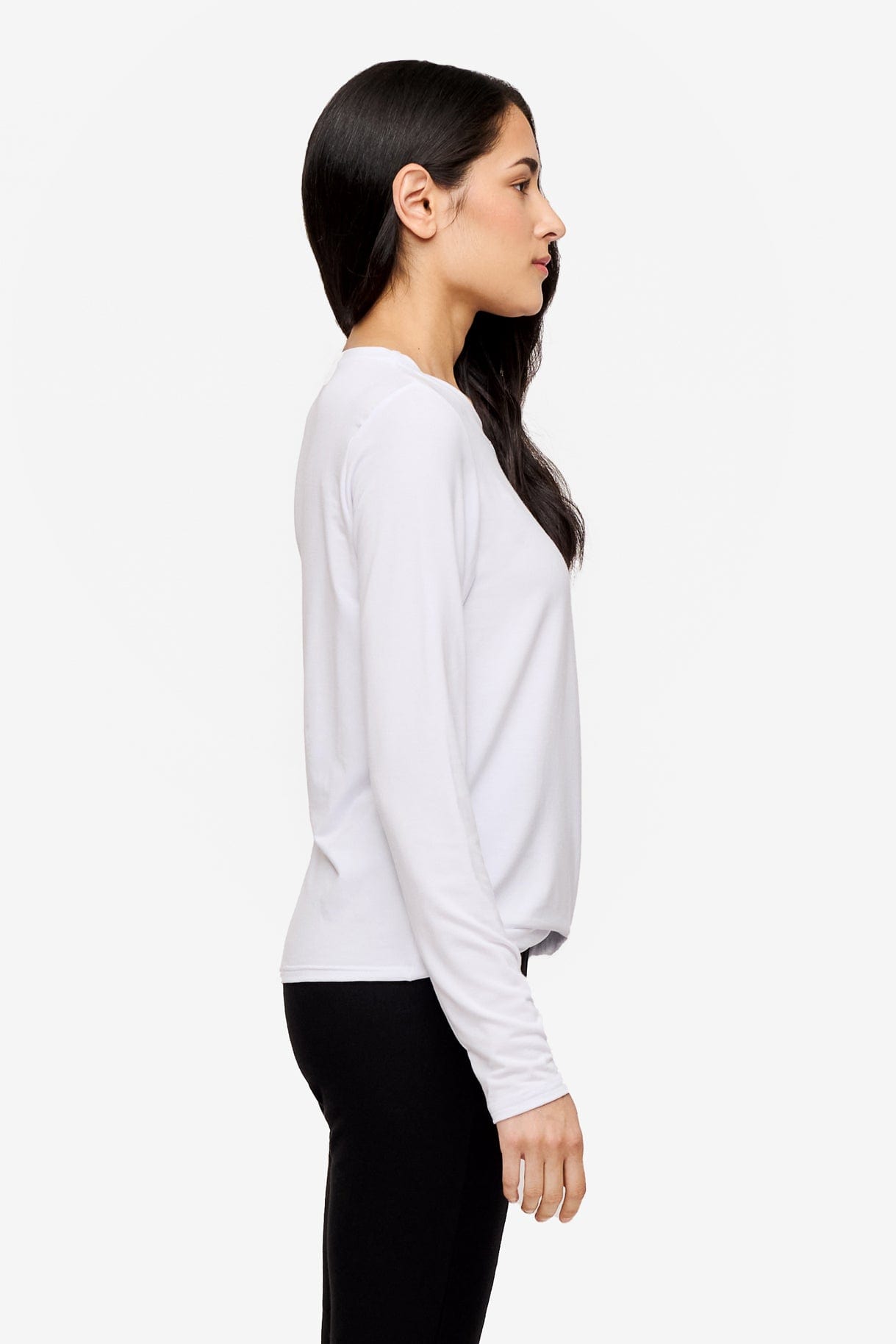 side of a woman wearing a long sleeve shirt with a twist at the front in white