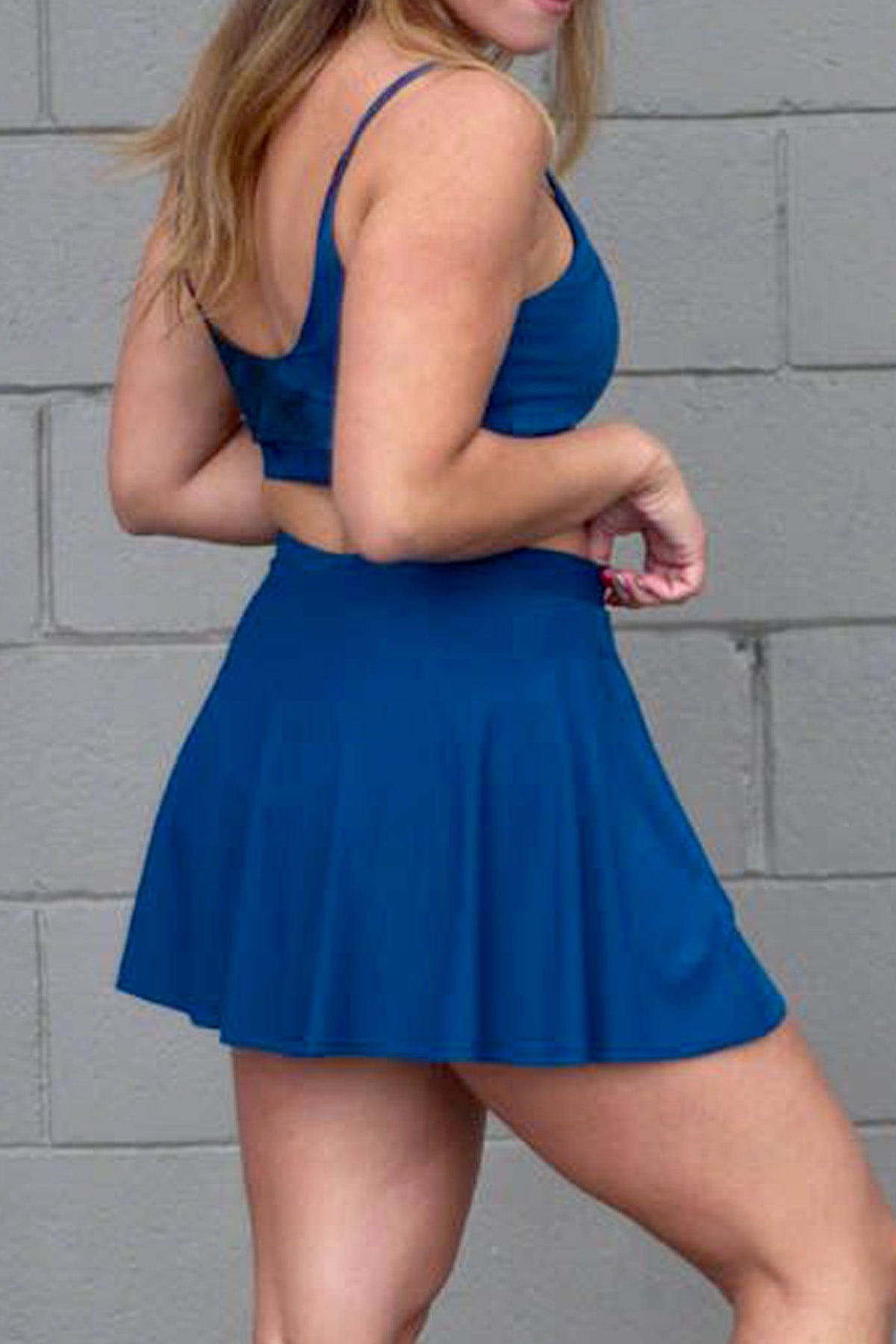 Side of a woman wearing a blue tennis skirt