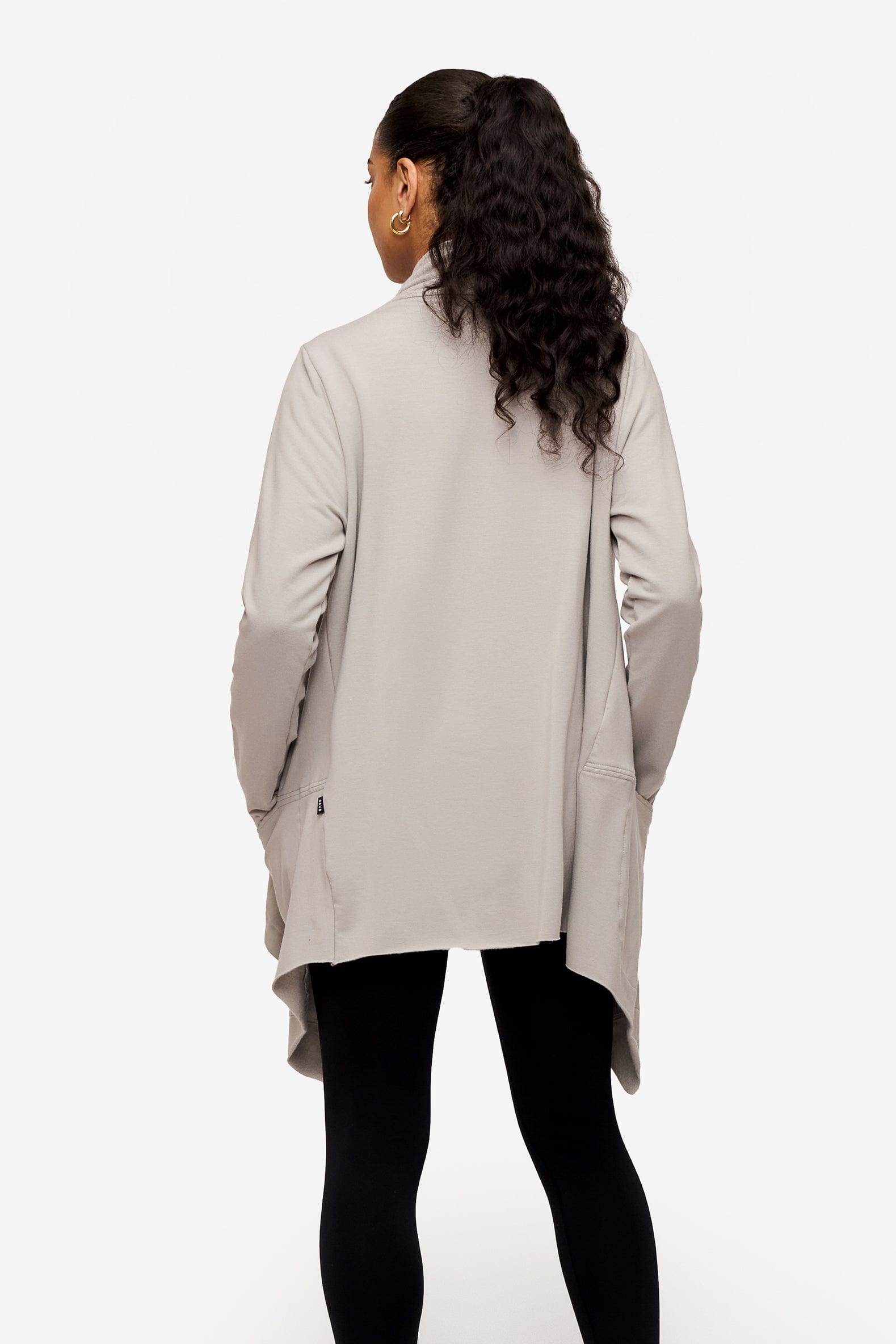 back of a woman wearing a drapey jacket in light grey