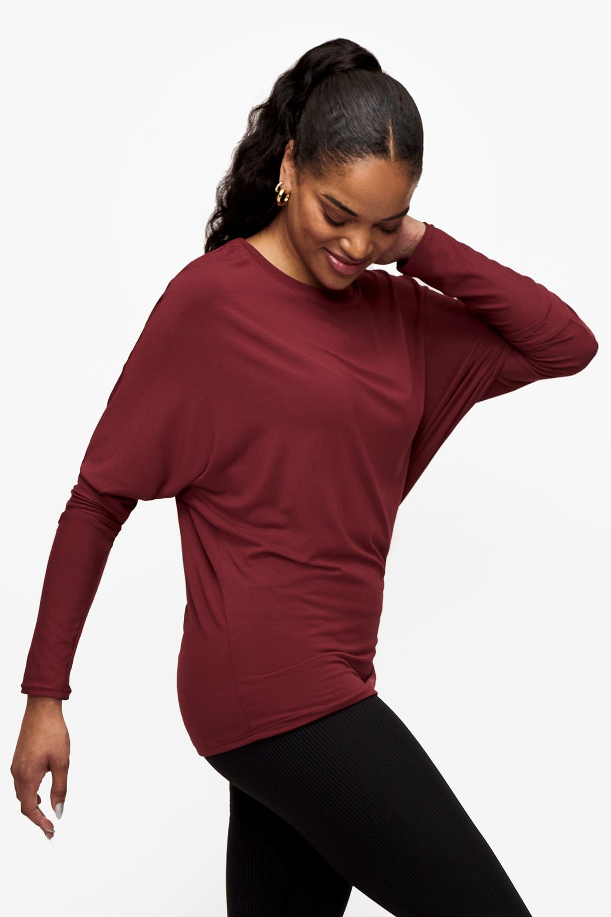 side of a woman wearing a dark red loose sleeve long sleeve shirt