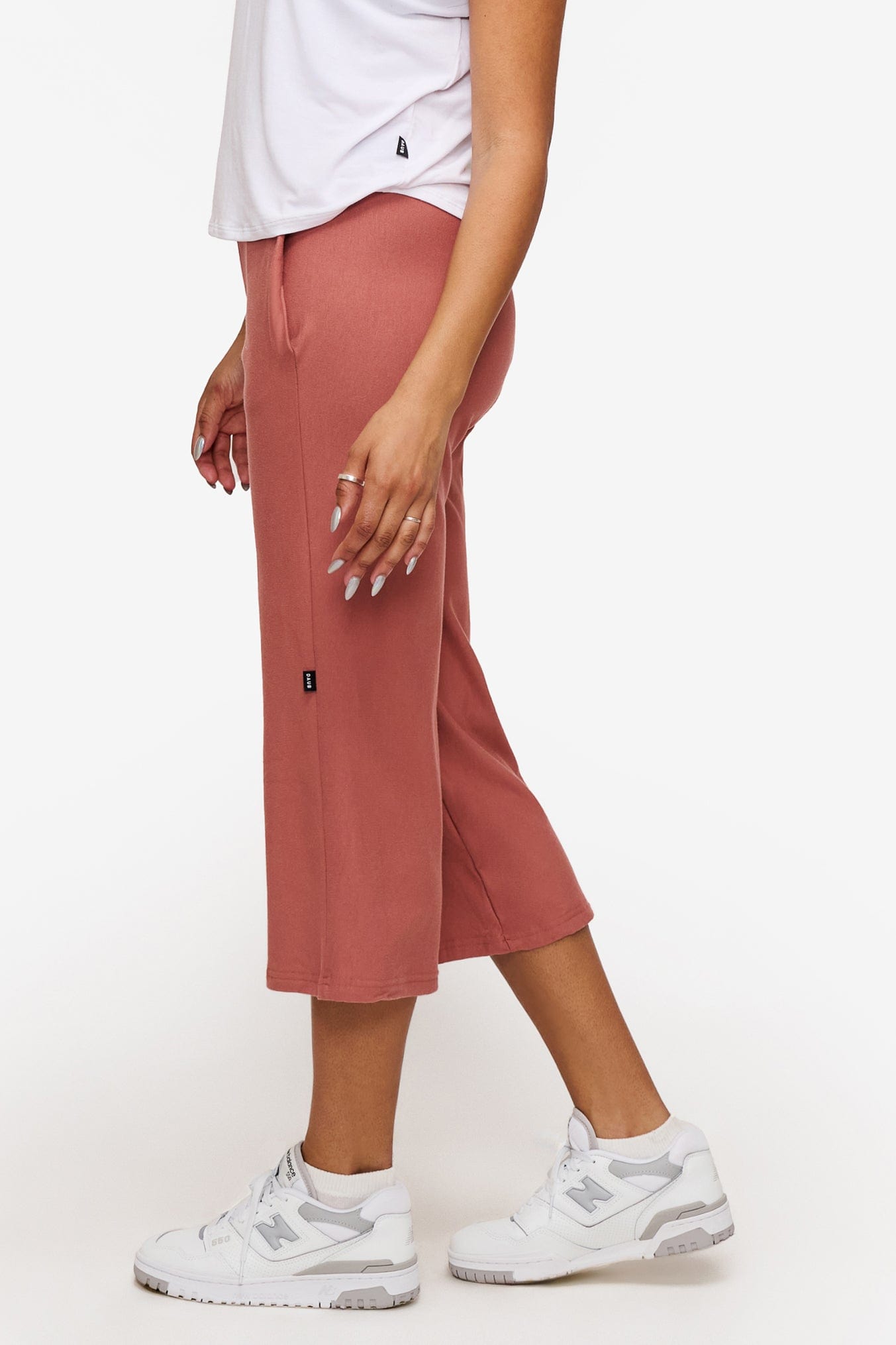 side of a woman wearing orange cropped sweatpants with drawstring
