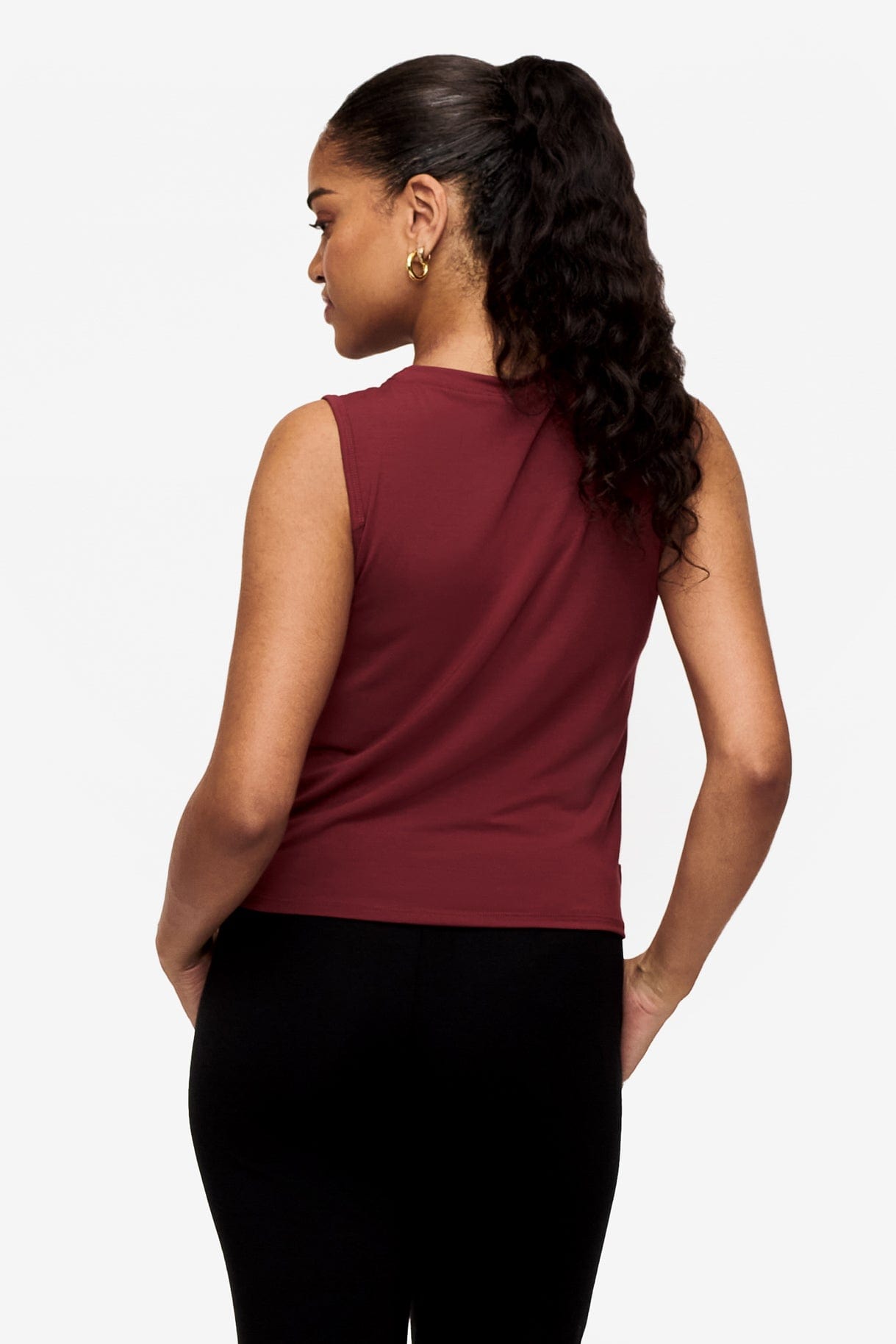 back of a woman wearing a sleeveless shirt with a twist at the front in deep red