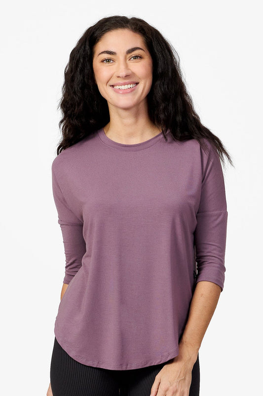 woman smiling wearing a light purple 3/4 length sleeve shirt