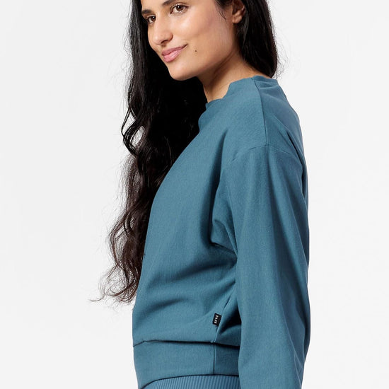 Side of a woman wearing teal sweatshirt