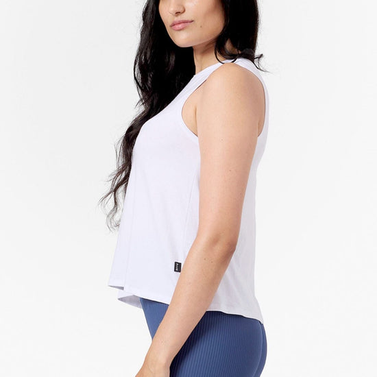 Side of a woman wearing a white tank and blue ribbed leggings