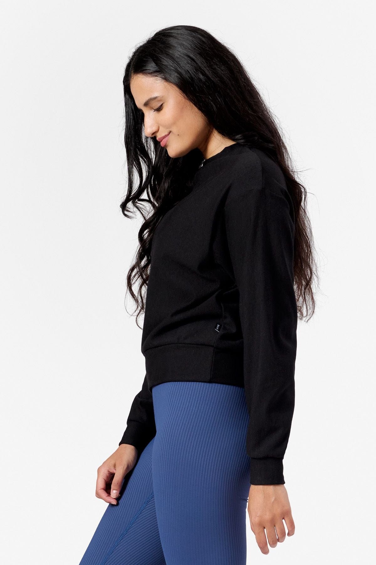Side of a woman wearing a black crew neck sweatshirt