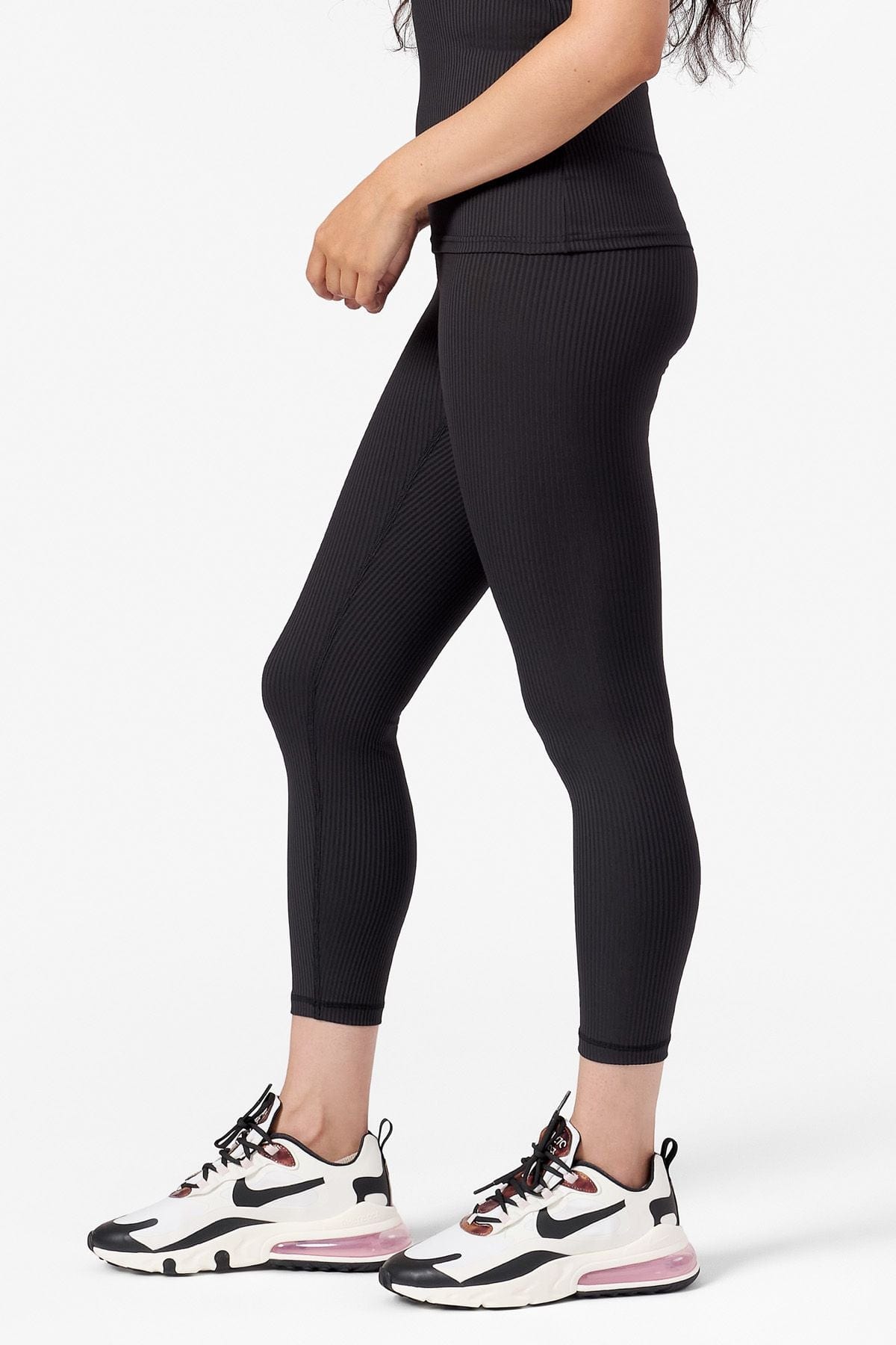 side view of a woman wearing black ribbed leggings in a mid length