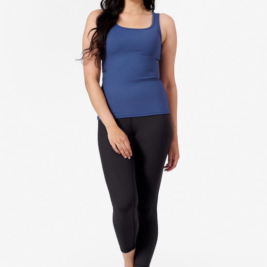 a woman wearing mid length black leggings and square neck tank top in blue