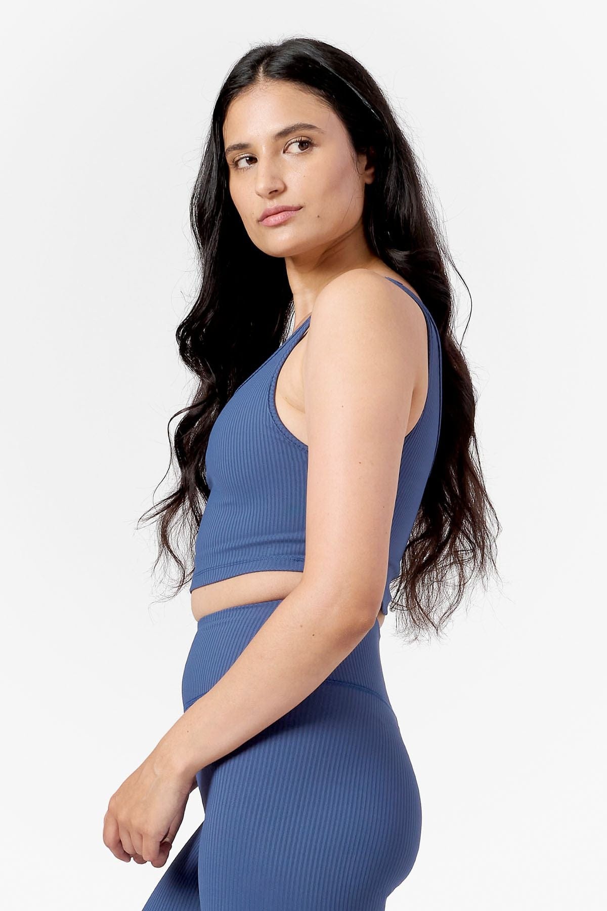 woman looking over her shoulder wearing a matching blue ribbed crop top and blue ribbed leggings