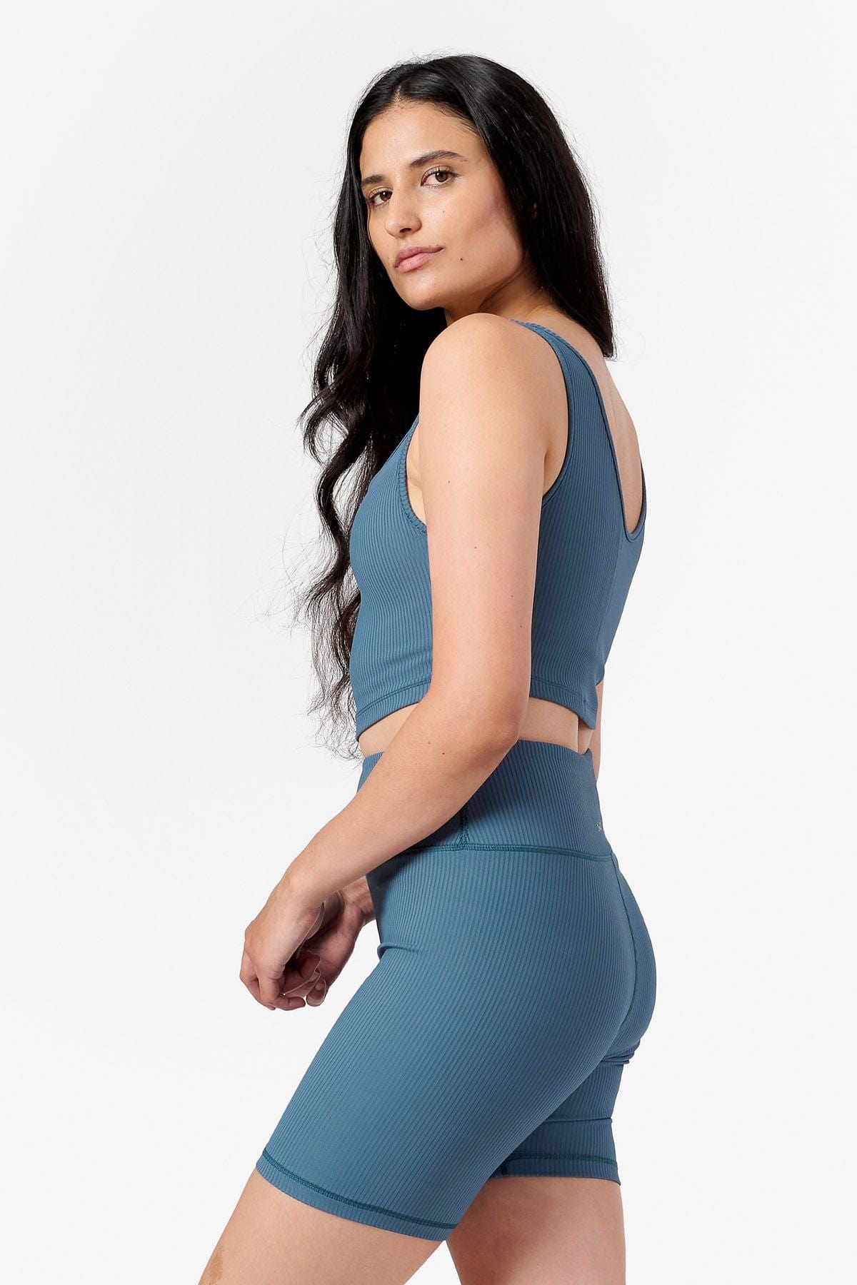 side of woman wearing a teal ribbed crop top and teal bike shorts