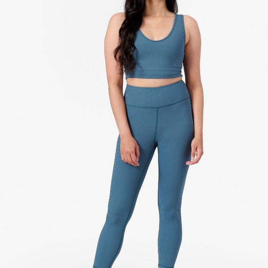 full view of woman wishing a matching ribbed sports set with crop top and leggings