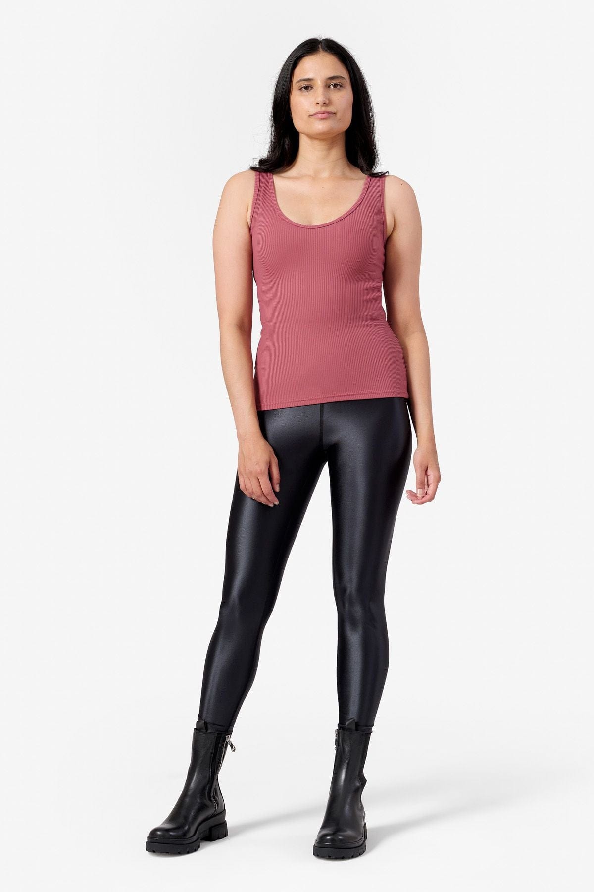 a woman wearing a ribbed pink tank top with black shiny leggings