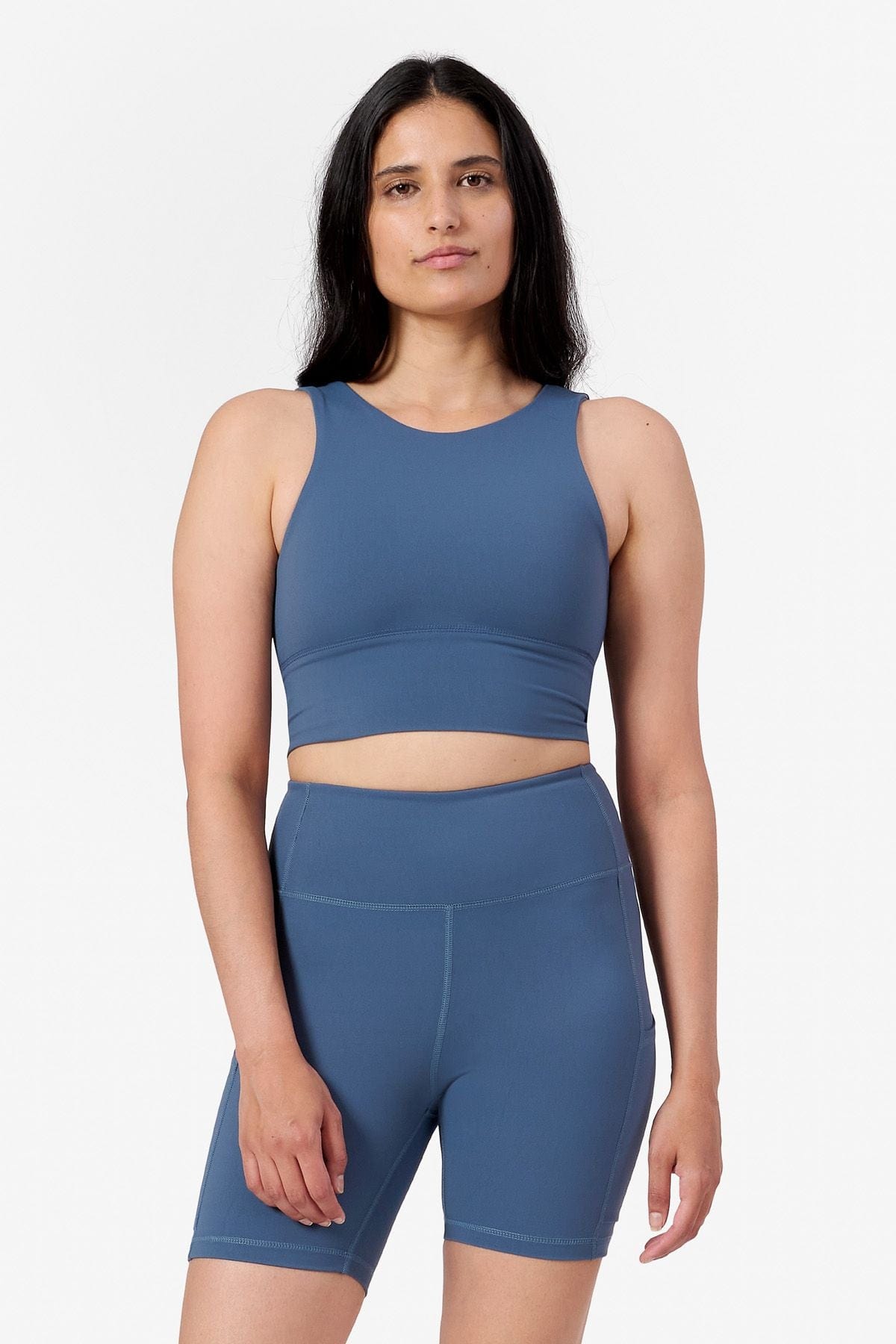 a woman wearing a matching set of blue sports bra and blue bike shorts with side pockets