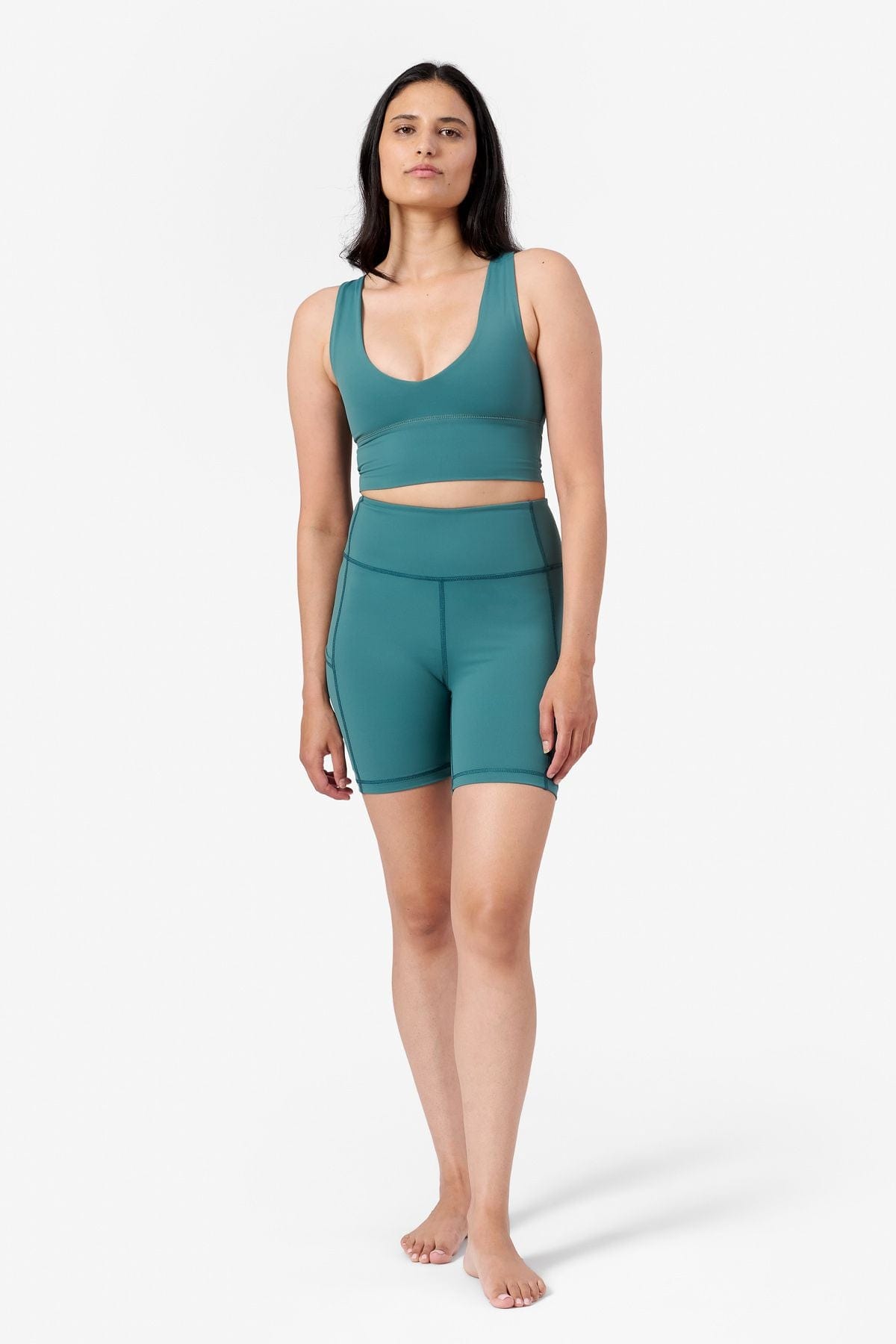 a woman wearing a matching teal sports bra with teal bike shorts that has pockets