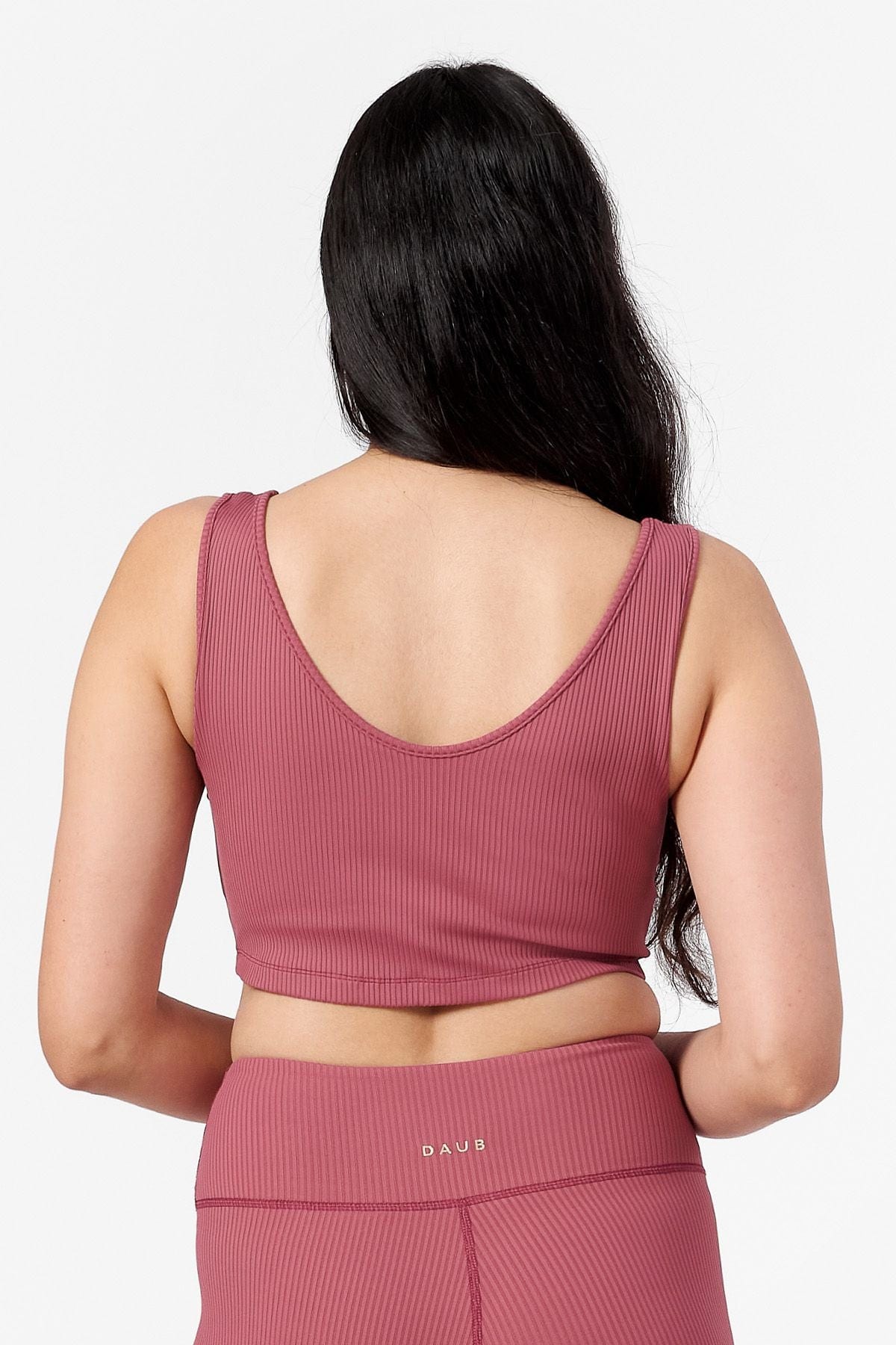 back of woman wearing reversible ribbed crop top in pink with round scoop side