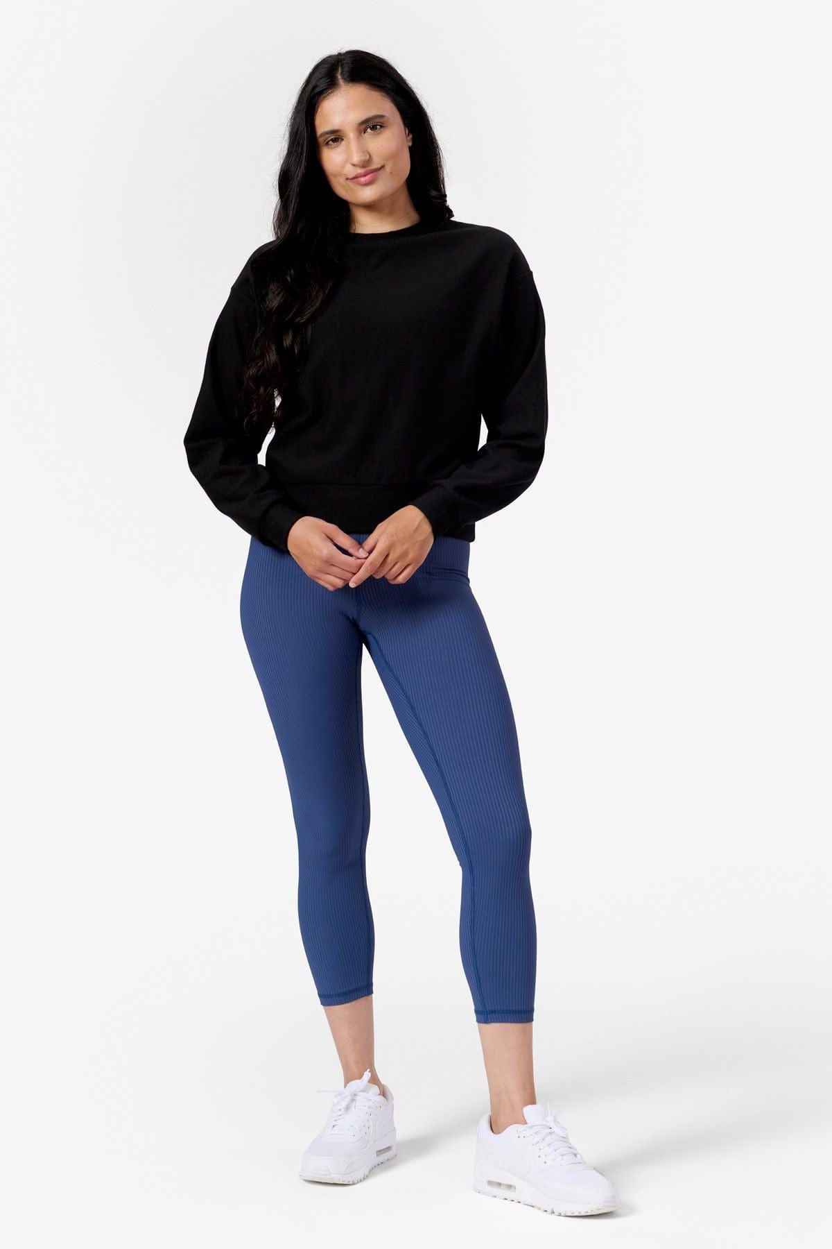 Woman wearing a black crew neck sweatshirt and Blue leggings