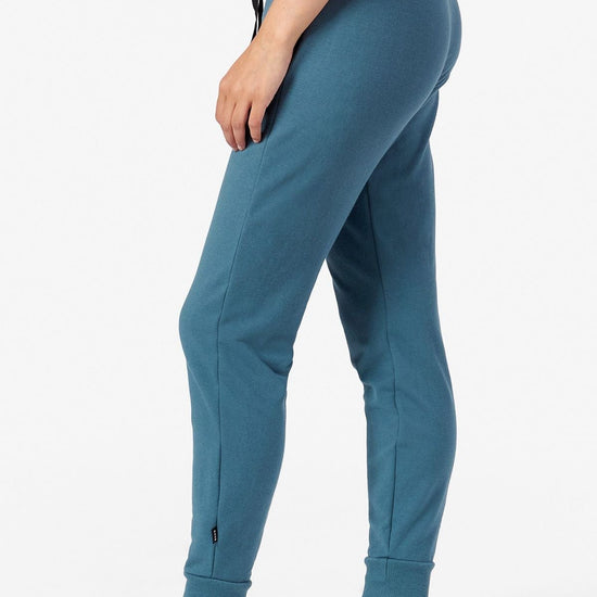 Side of a woman wearing teal joggers 