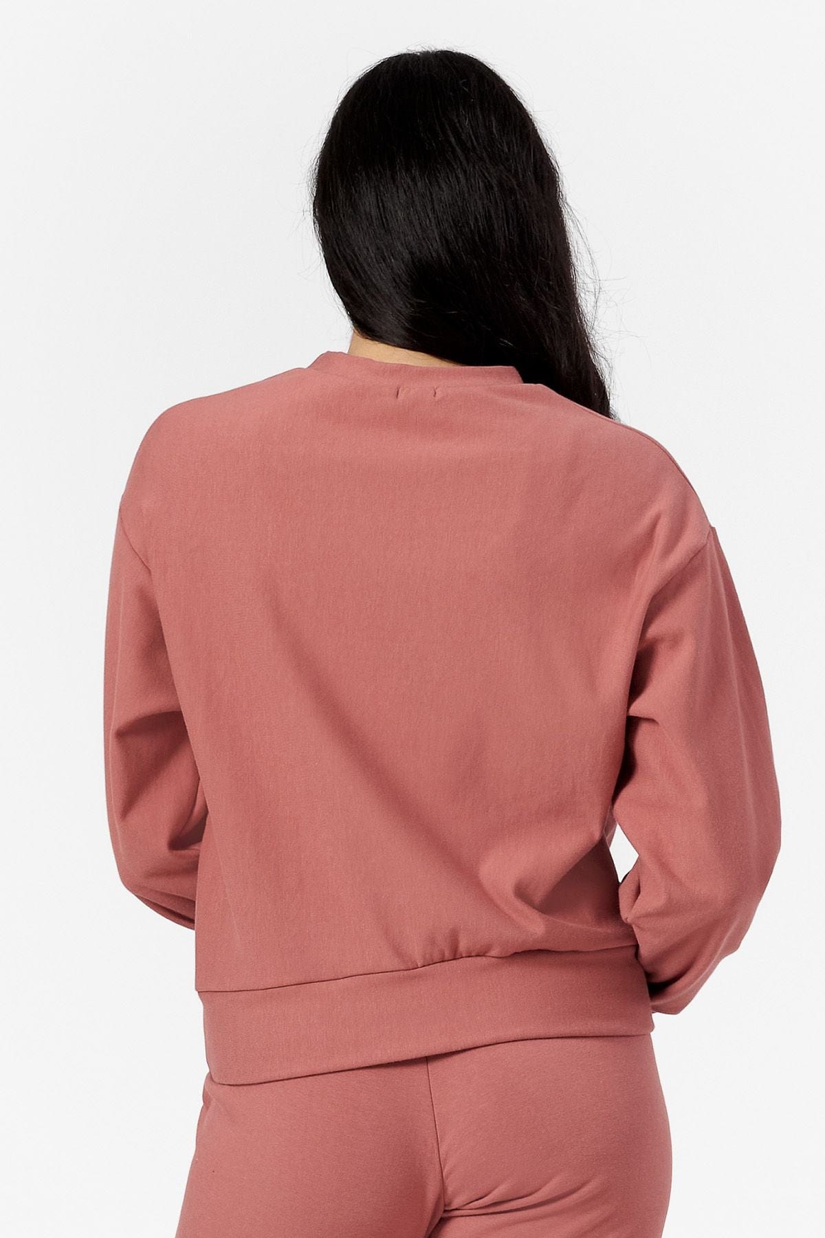 Back of a woman wearing a light rust crew neck