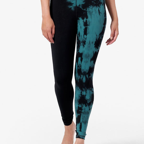 half view of a woman wearing tie dye teal and black leggings which are ankle length