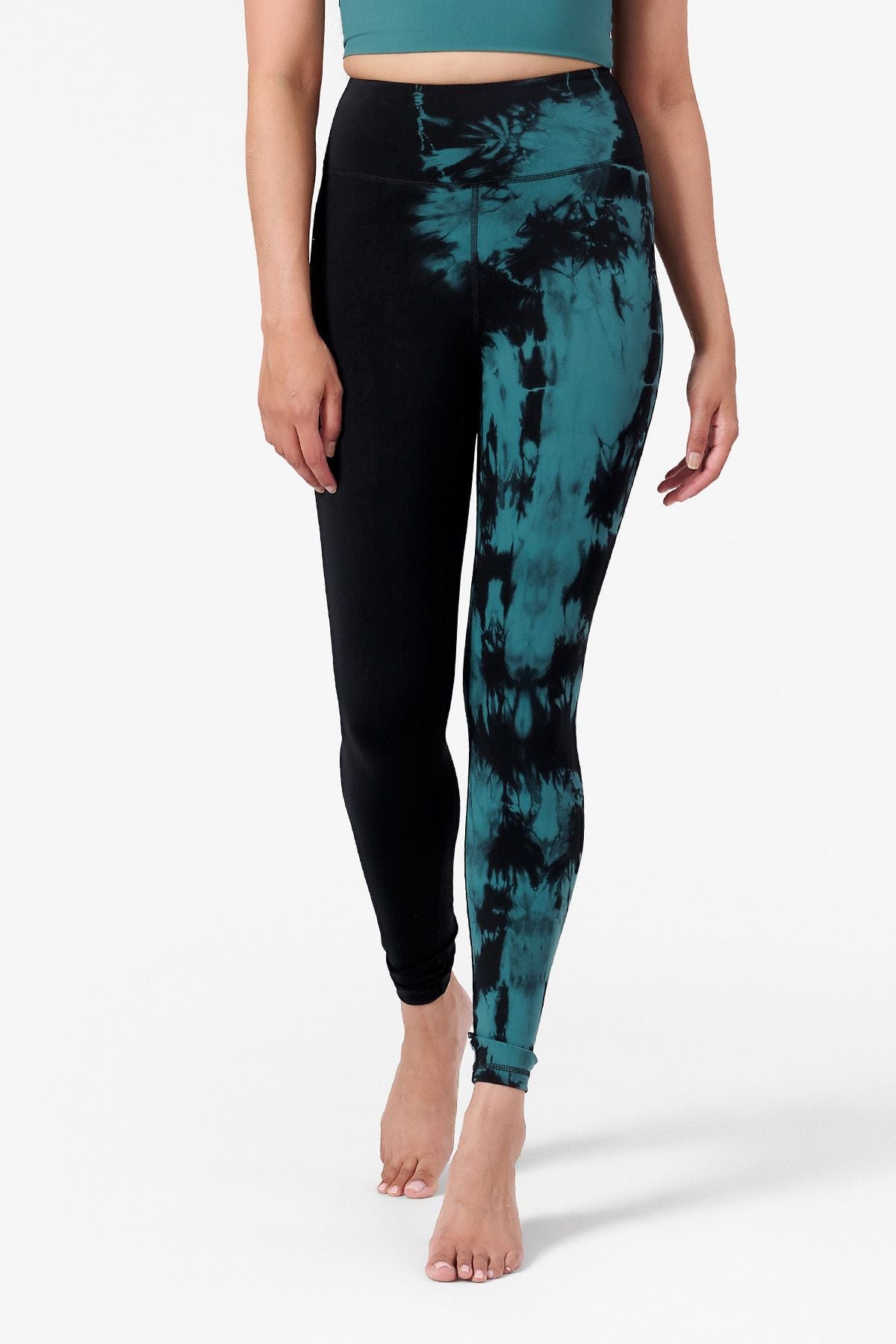 half view of a woman wearing tie dye teal and black leggings which are ankle length