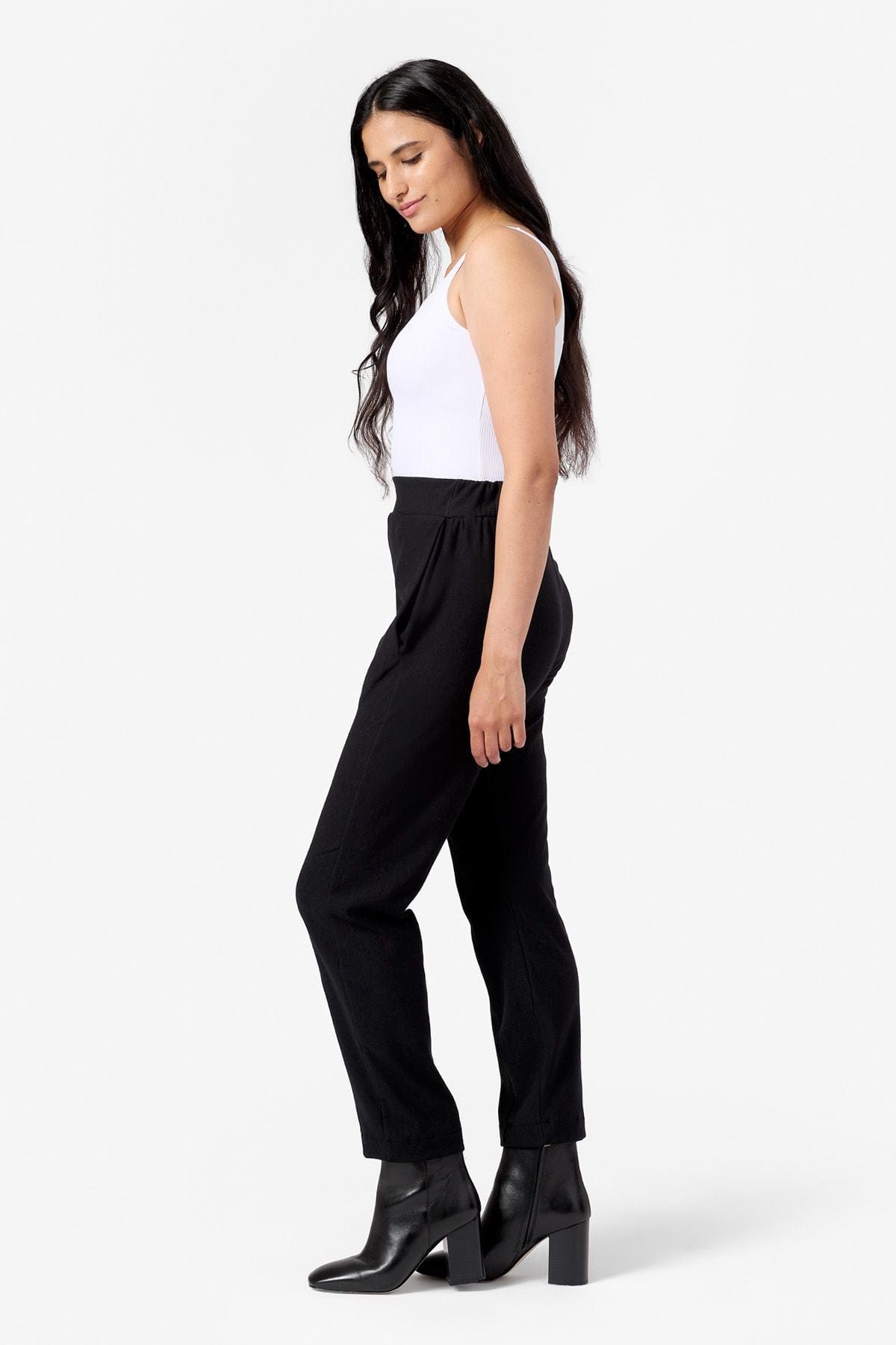 side view of a woman wearing a white tank top and fleece pants with pockets in black