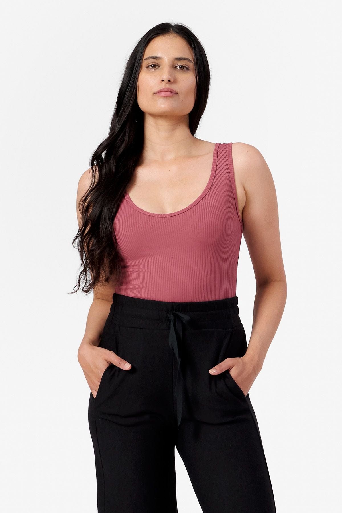 woman wearing a pink ribbed tank top with a low scoop neck and black joggers