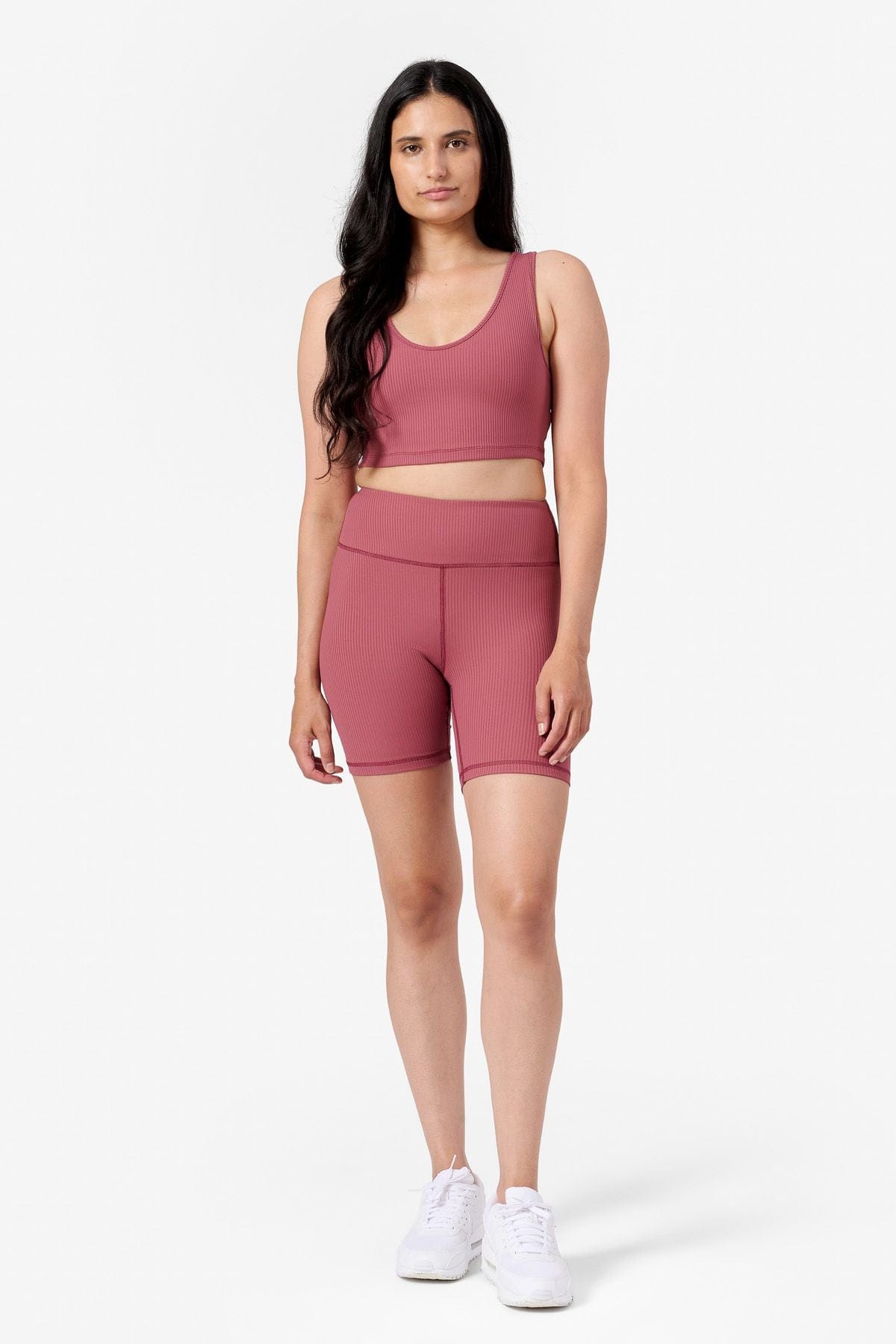 a woman wearing a matching pink ribbed bike shorts and a pink ribbed crop top