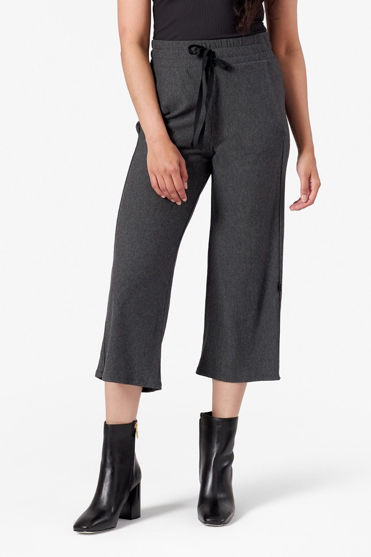 a woman wearing black heeled boots and cropped wide leg sweatpants with black waist ribbon