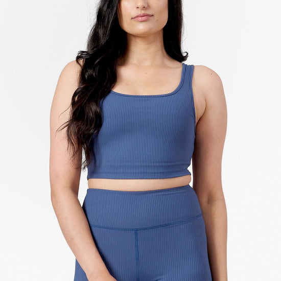 front of a woman wearing square side of a reversible ribbed sports bra in blue
