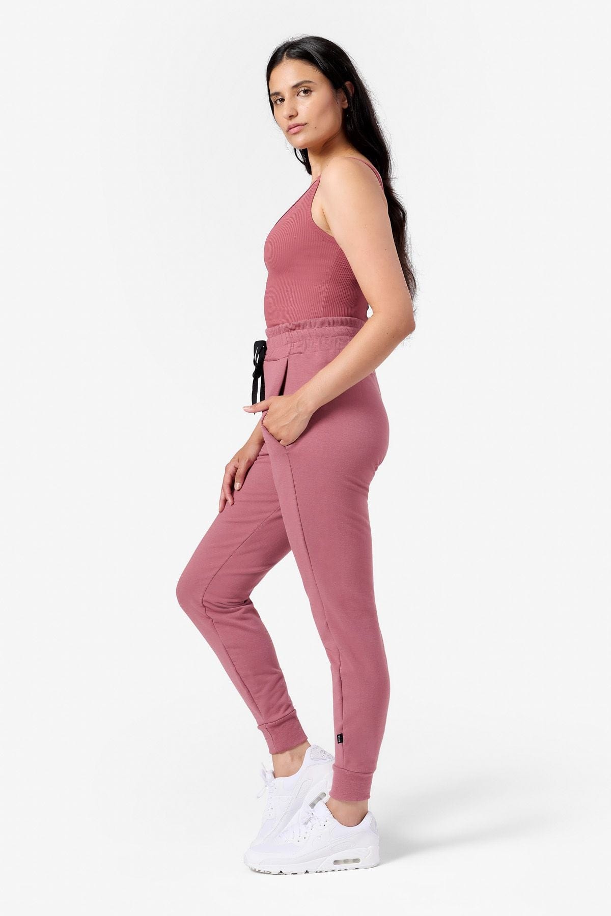 side view of a woman wearing pink joggers with pockets and a pink tank top