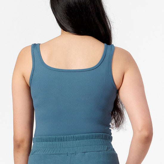 back view of woman wearing a square neck tank top in  a teal ribbed fabric.