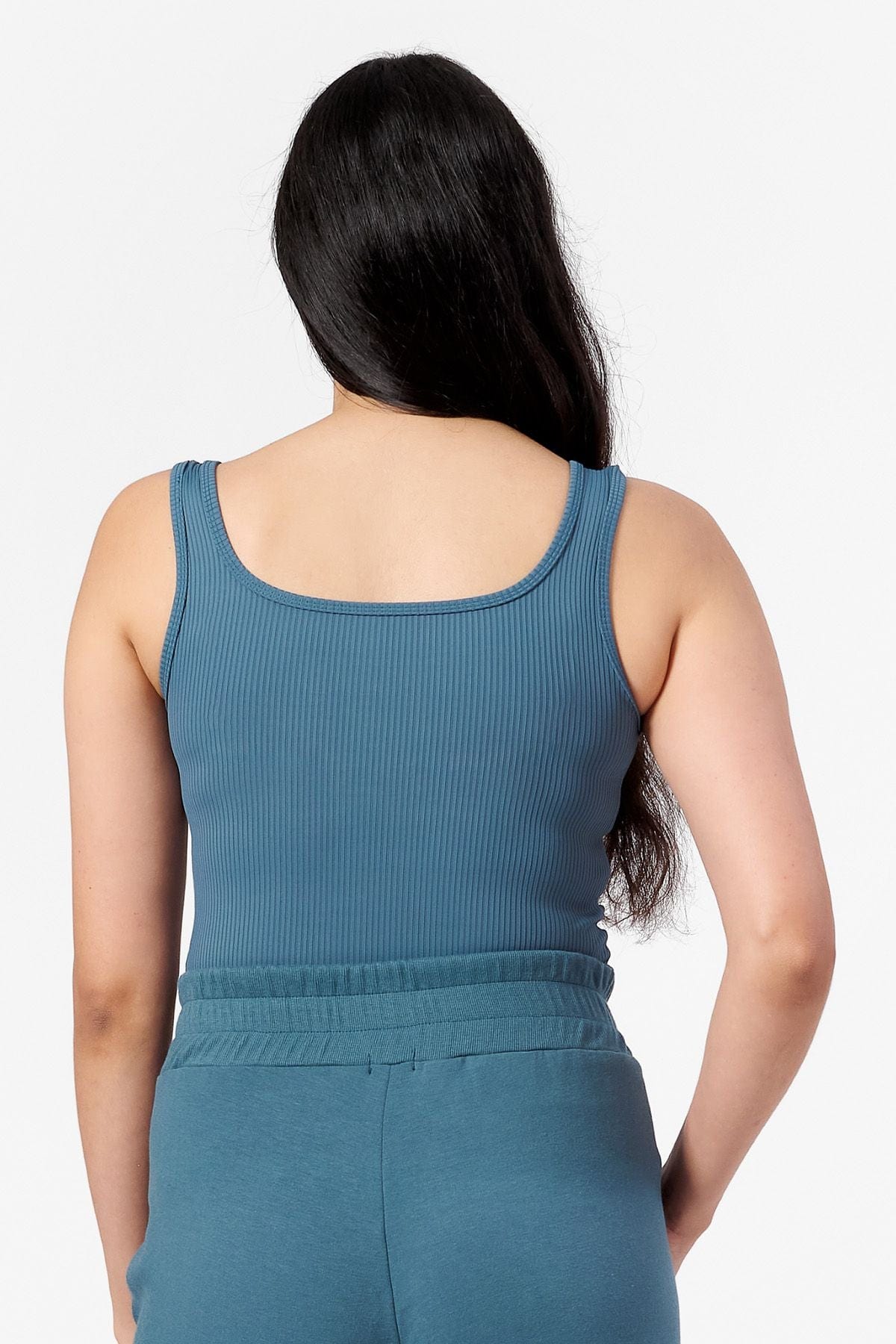 back view of woman wearing a square neck tank top in a teal ribbed fabric.