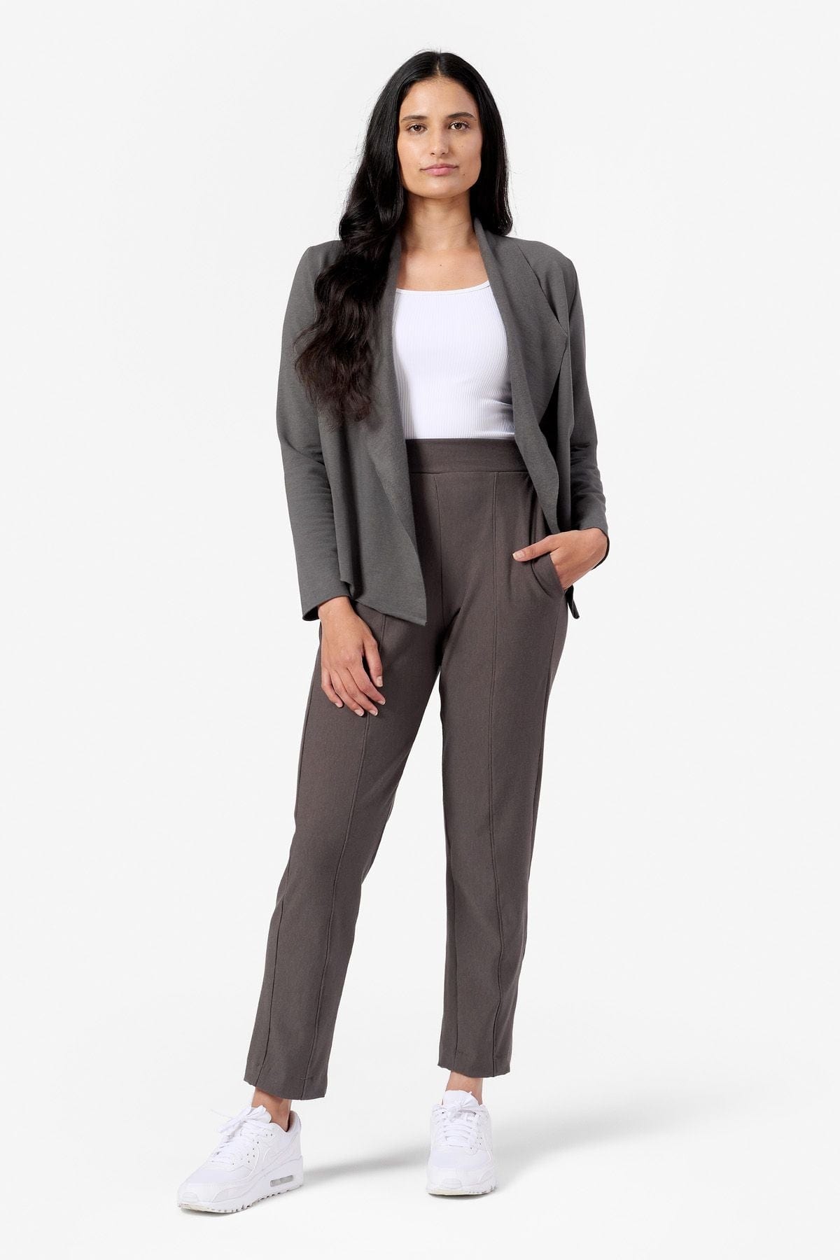 a woman wears a grey short jacket with a white ribbed tank top and brown ankle length fleece pants