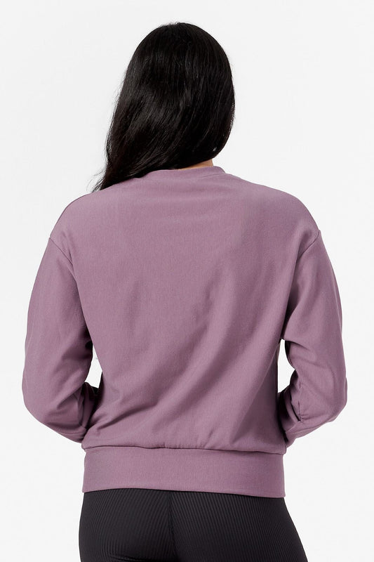 Back of a woman wearing a purple crew neck sweatshirt