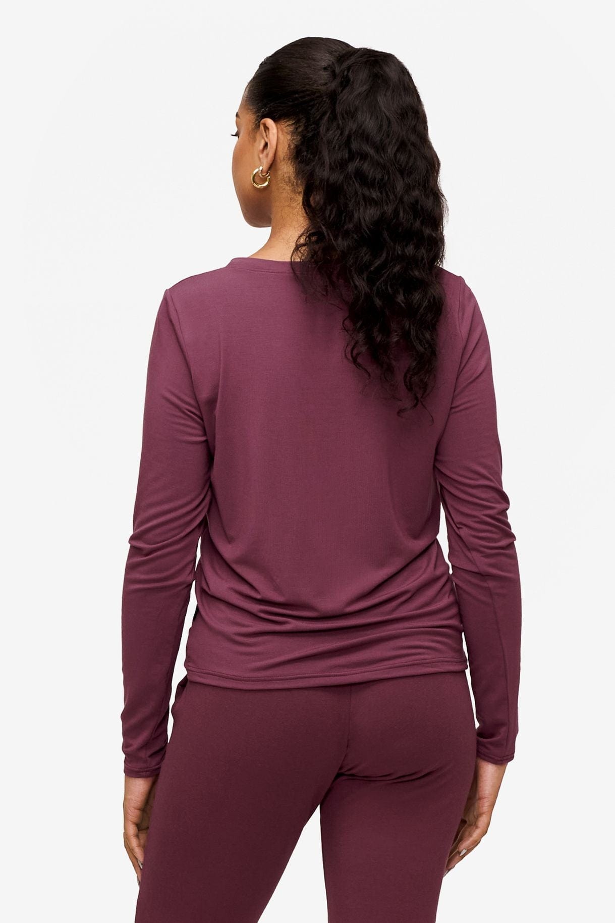 back of a woman wearing a deep pink long sleeve top with twist in the front