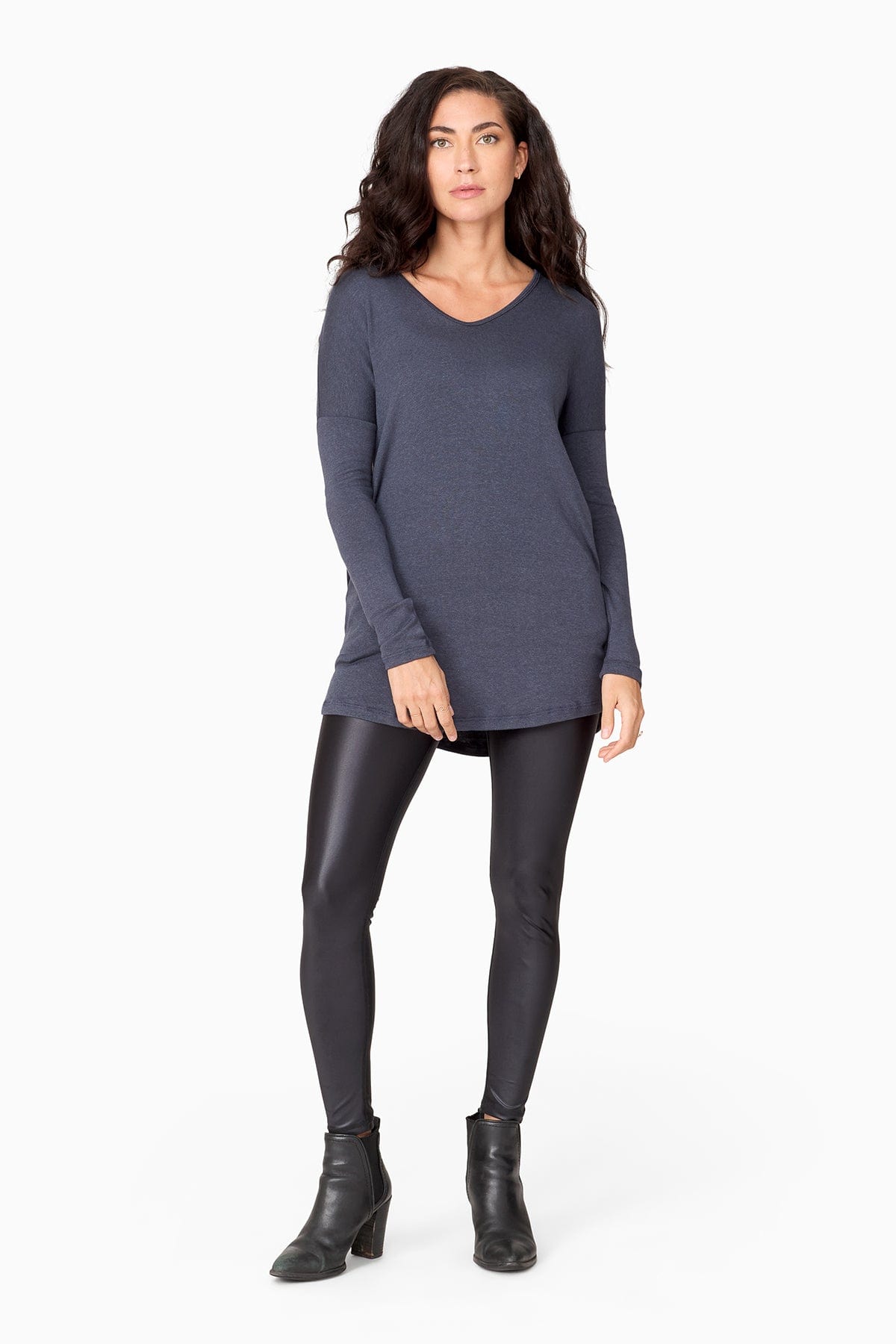Woman wearing a long sleeve blue sweater and liquid black leggings.