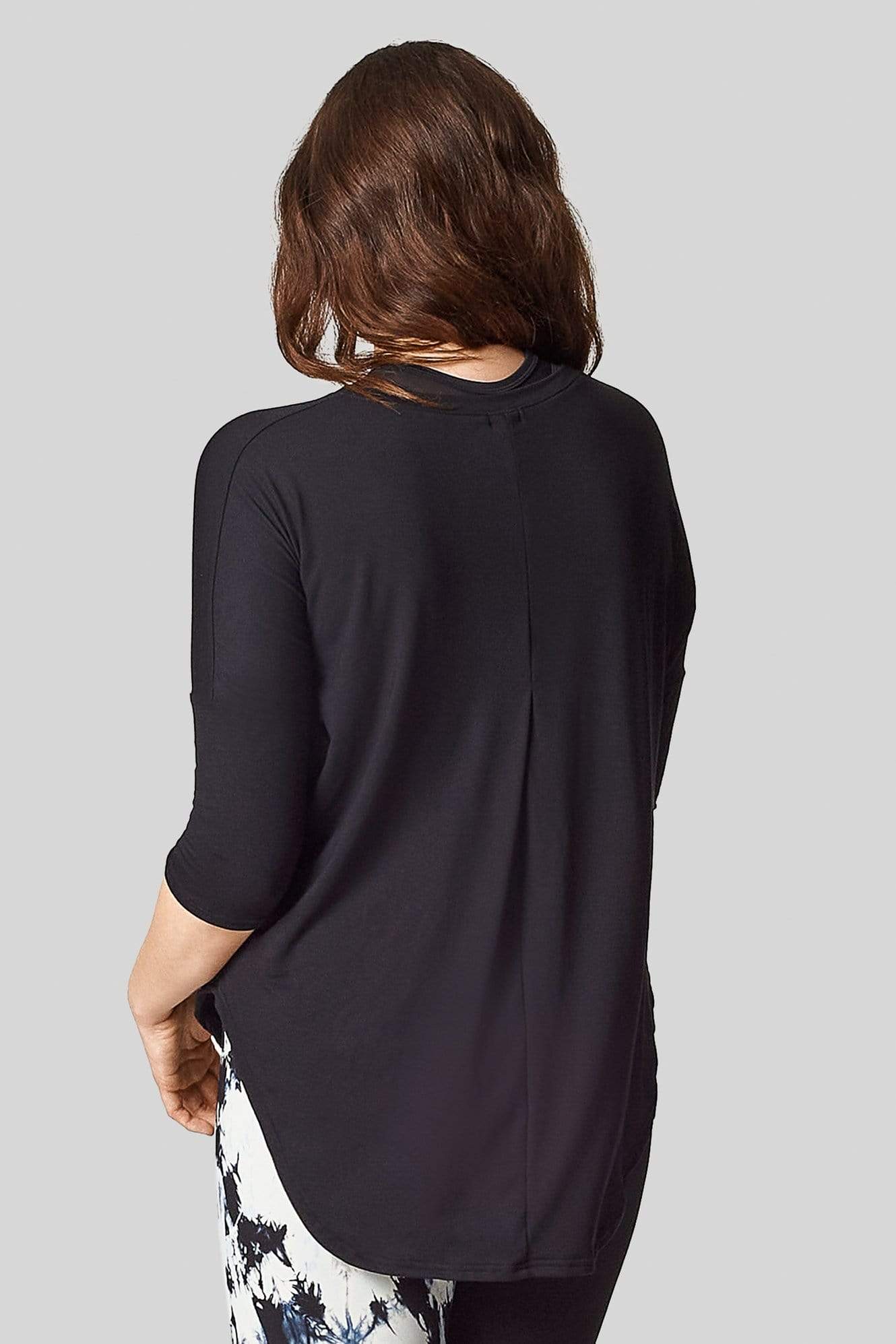 A brunette women is wearing a 3/4 length sleeve tee shirt with a pleat in the back starting at the bust.