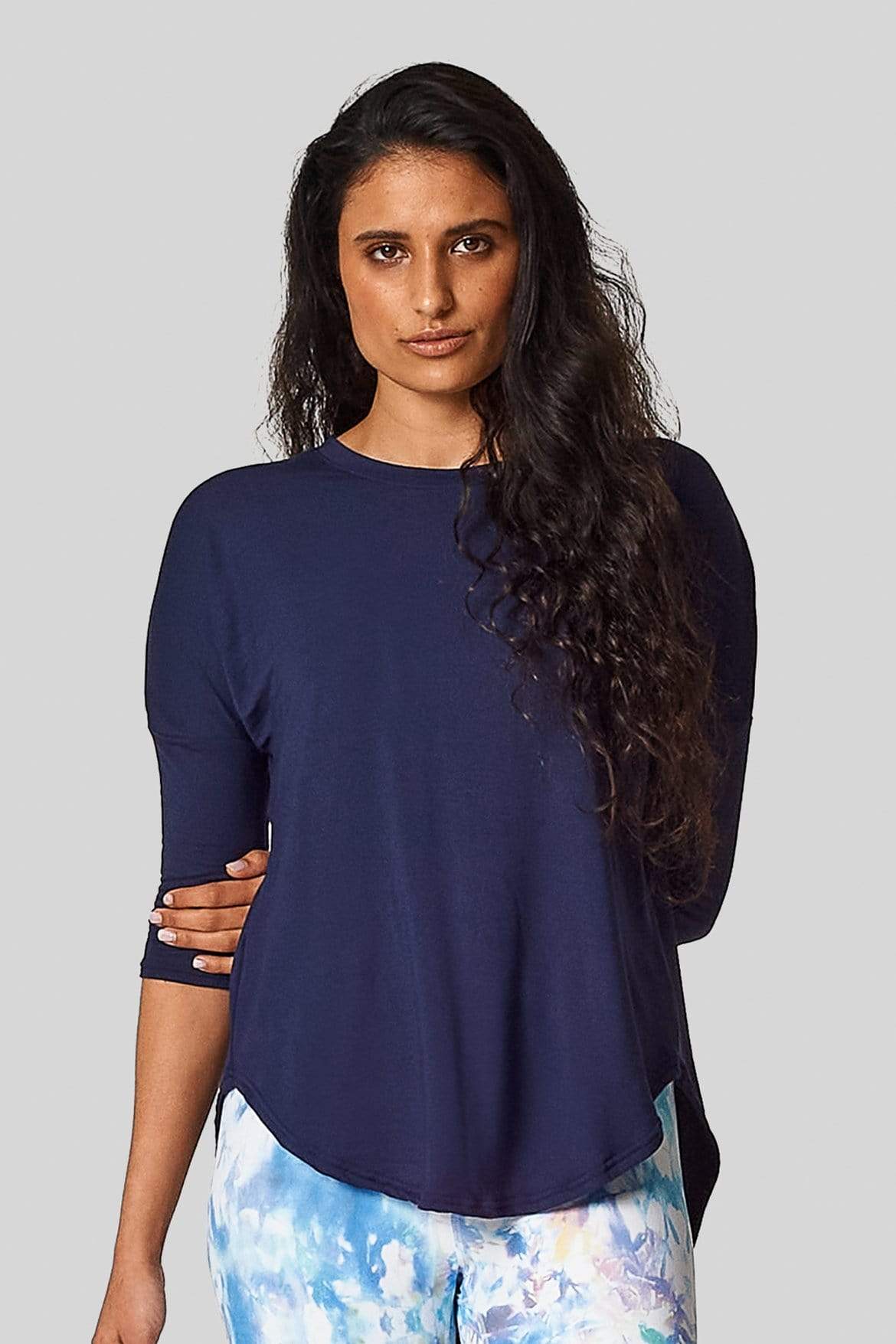 A woman wears a navy teeshirt with 3/4 length sleeves and printed leggings.